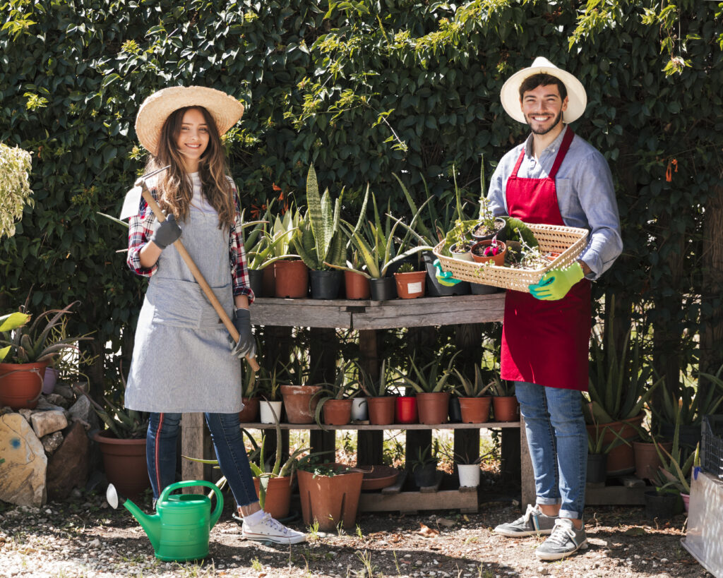Horticultural Therapy Certification 2026-A-smiling-couple-wearing-aprons-and-straw-hats-posing-outdoors-with-a-garden-hoe-and-a-basket-of-plant-starts-in-front-of-a-potting-bench.-Image-of-trained-professionals certificat