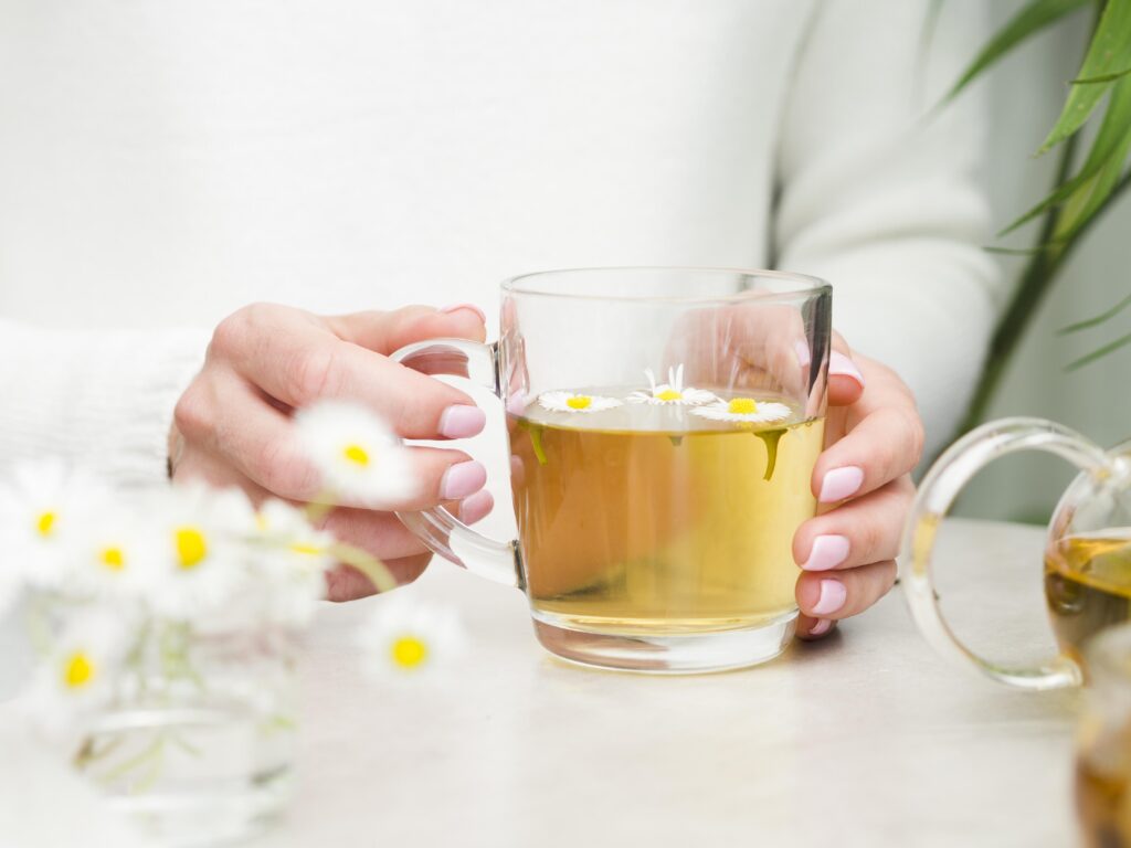Front view of a woman holding a glass of tea-Morning Sickness, herbal tea for Pregnancy