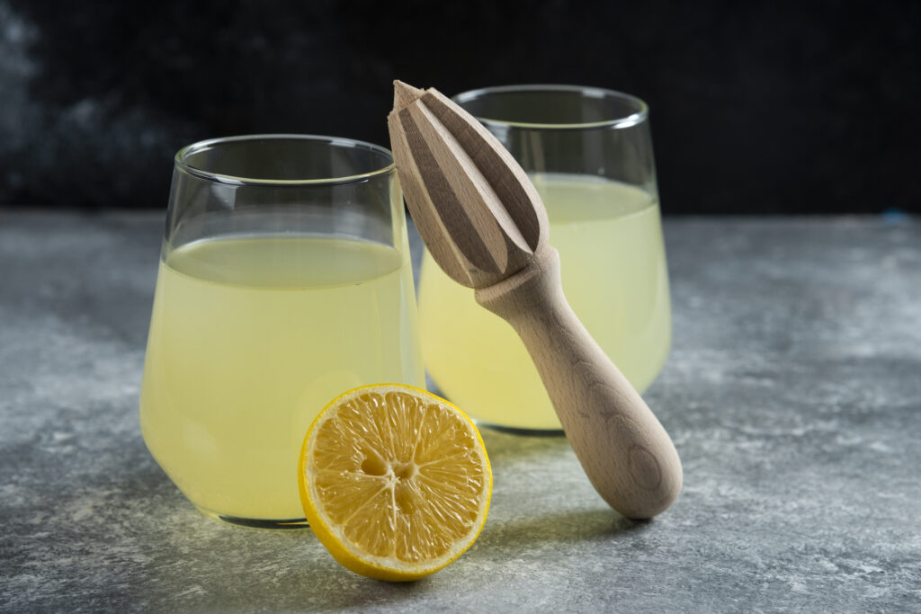 Cups of lemonade with slice of lemon and wooden reamer for Morning Sickness, herbal tea for Pregnancy