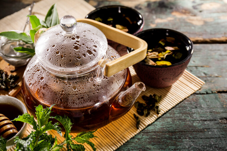 Steaming glass teapot and ingredients for tea vs herbal tea infusion guide