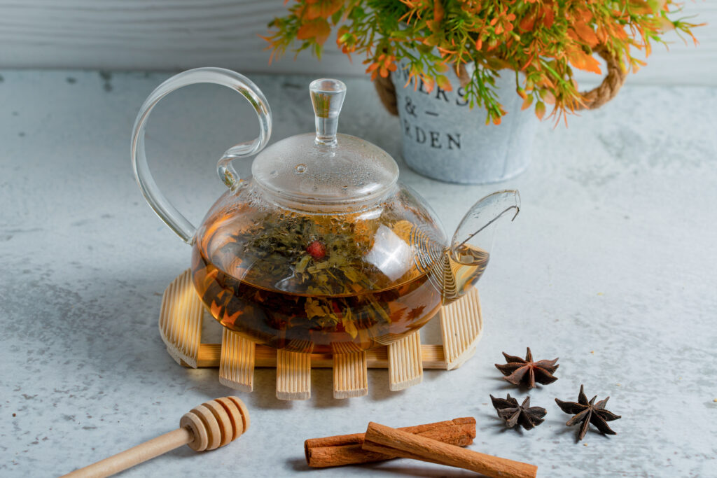 glass teapot full of freshly brewed tea on a grey wall-Tea vs Herbal Tea vs Infusion