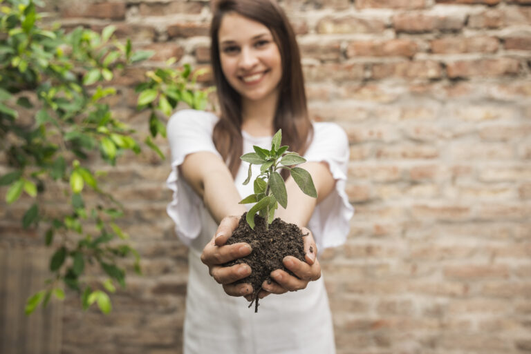 the garden therapy - a woman-smiling-holding-a-small-plant-with-soil for horticultural therapy